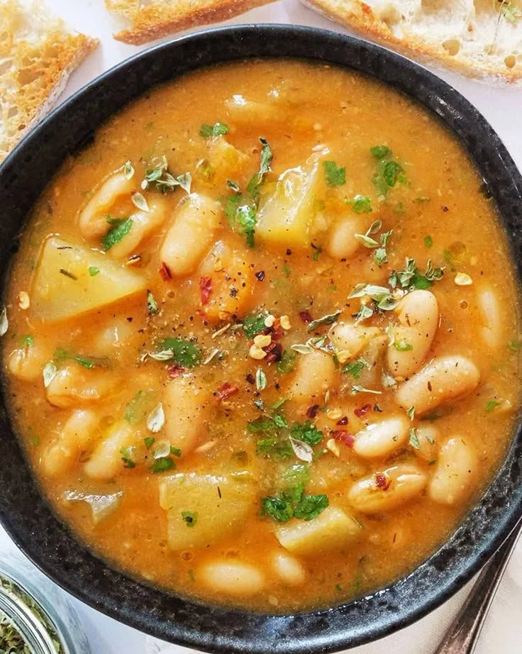 Bowl of cozy potato and bean soup garnished with herbs